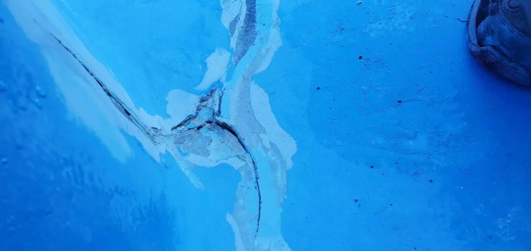 A medium closeup of a large crack in the floor of a fiberglass pool.