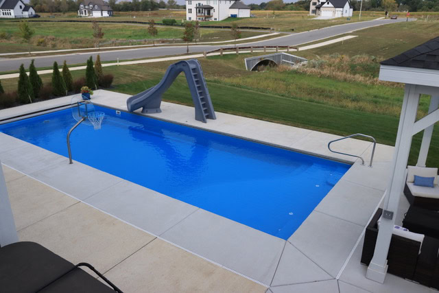 A backyard featuring a finished fiberglass pool with a slide and gazebo.