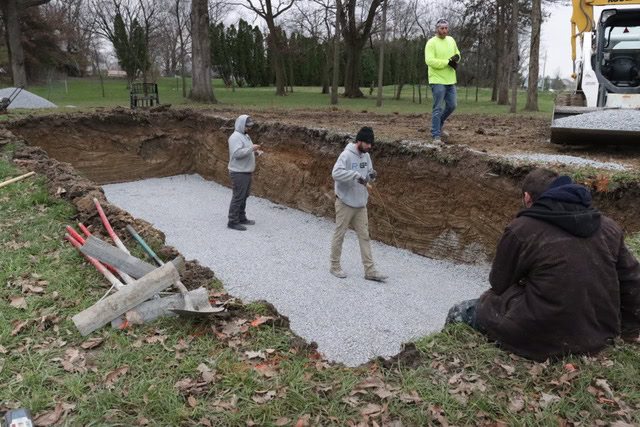 Four men inspecting an excavated pool hole.