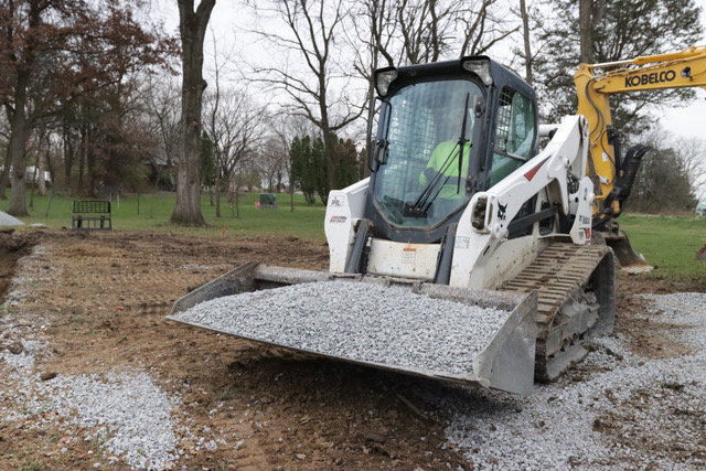 Excavator preparing to dump gravel in a pool hole.