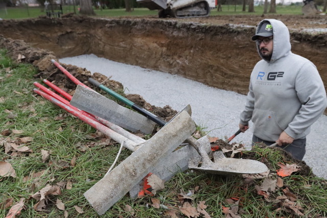 Man gathering tools and setting them outside of a pool hole.