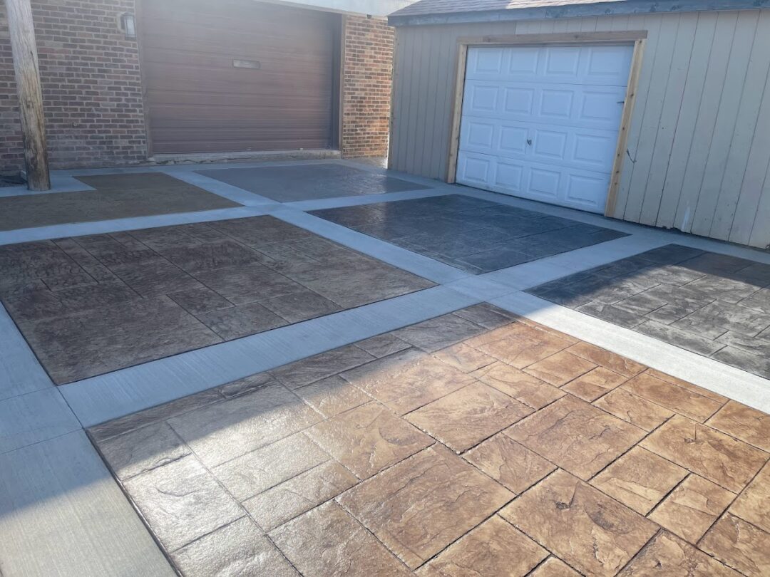 Six square sections of stamped concrete in a parking lot in front of two garage doors. 