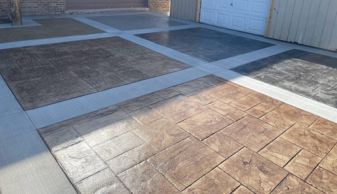 Photo of an area in front of a garage featuring six squares of different stamped designs and colors.