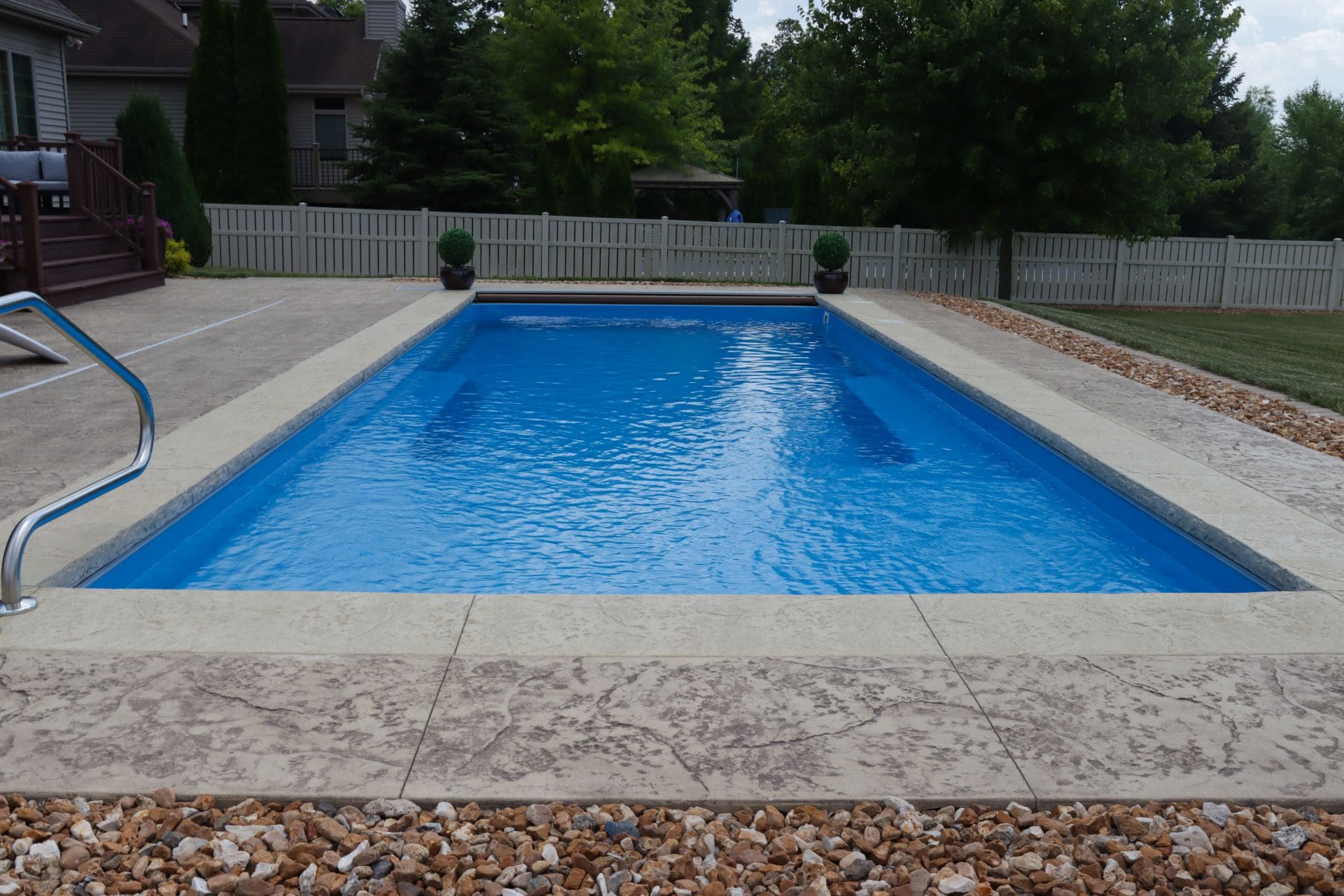 IMG_8155.jpg-Sized Photo of an inground pool surrounded by a stamped concrete pool deck with a few feet of gravel around the patio. Grass can be seen beyond gravel.