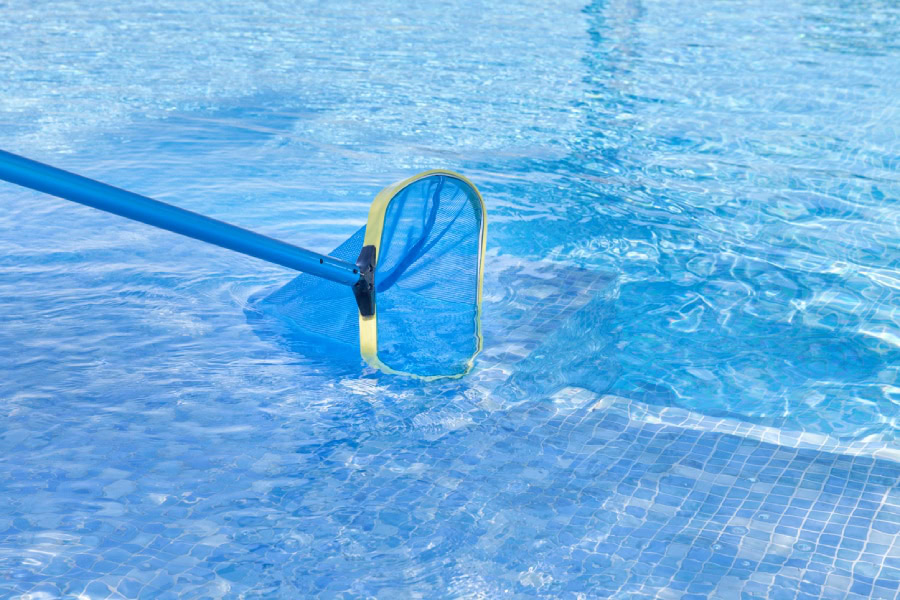 A medium wide shot of a net skimming a swimming pool.