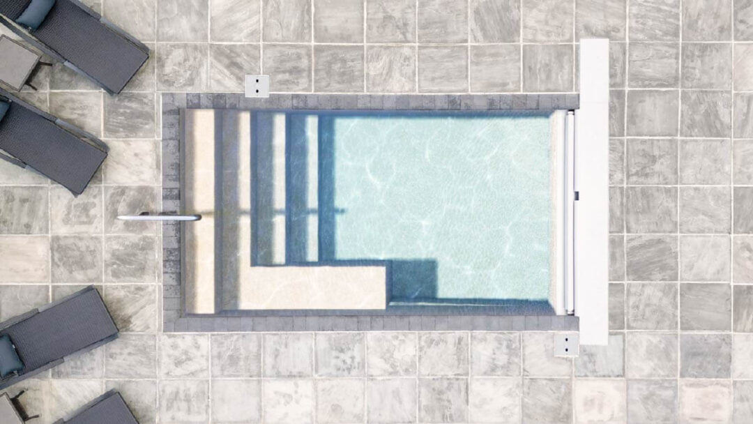 Aerial landscape 3D-rendered image of a rectangular light blue inground pool surrounded by light gray square brick pavers. Outside the pool parallel to the shallow-end width are four lounge chairs cut off by the left-side of the image. 