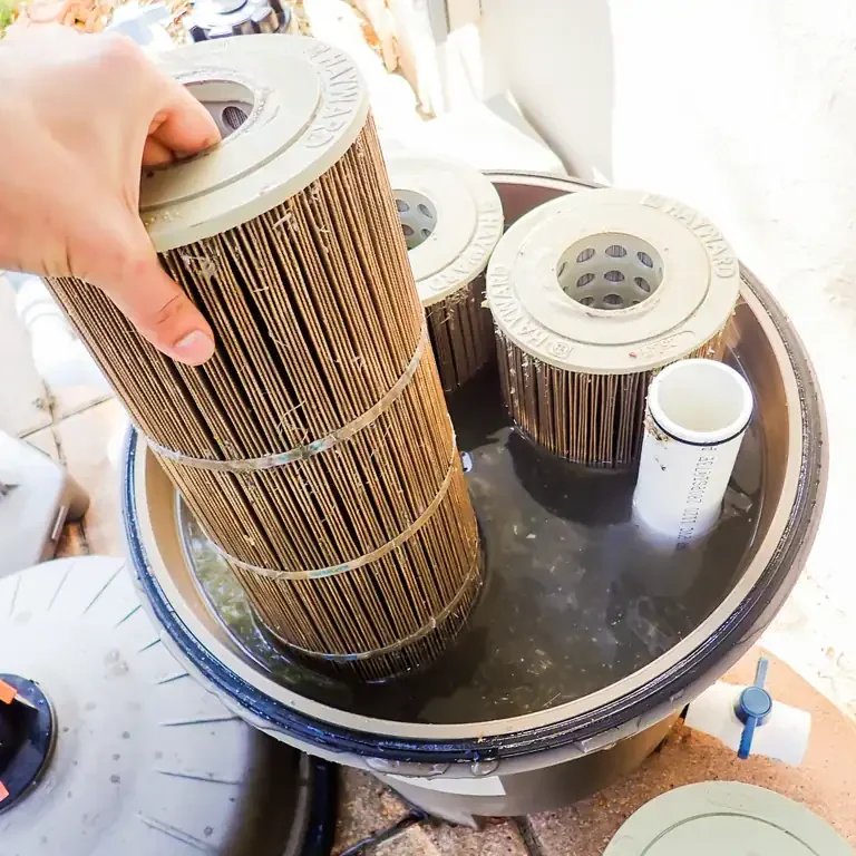 Dirty pool cartridges being removed from a cartridge filter full of black water.