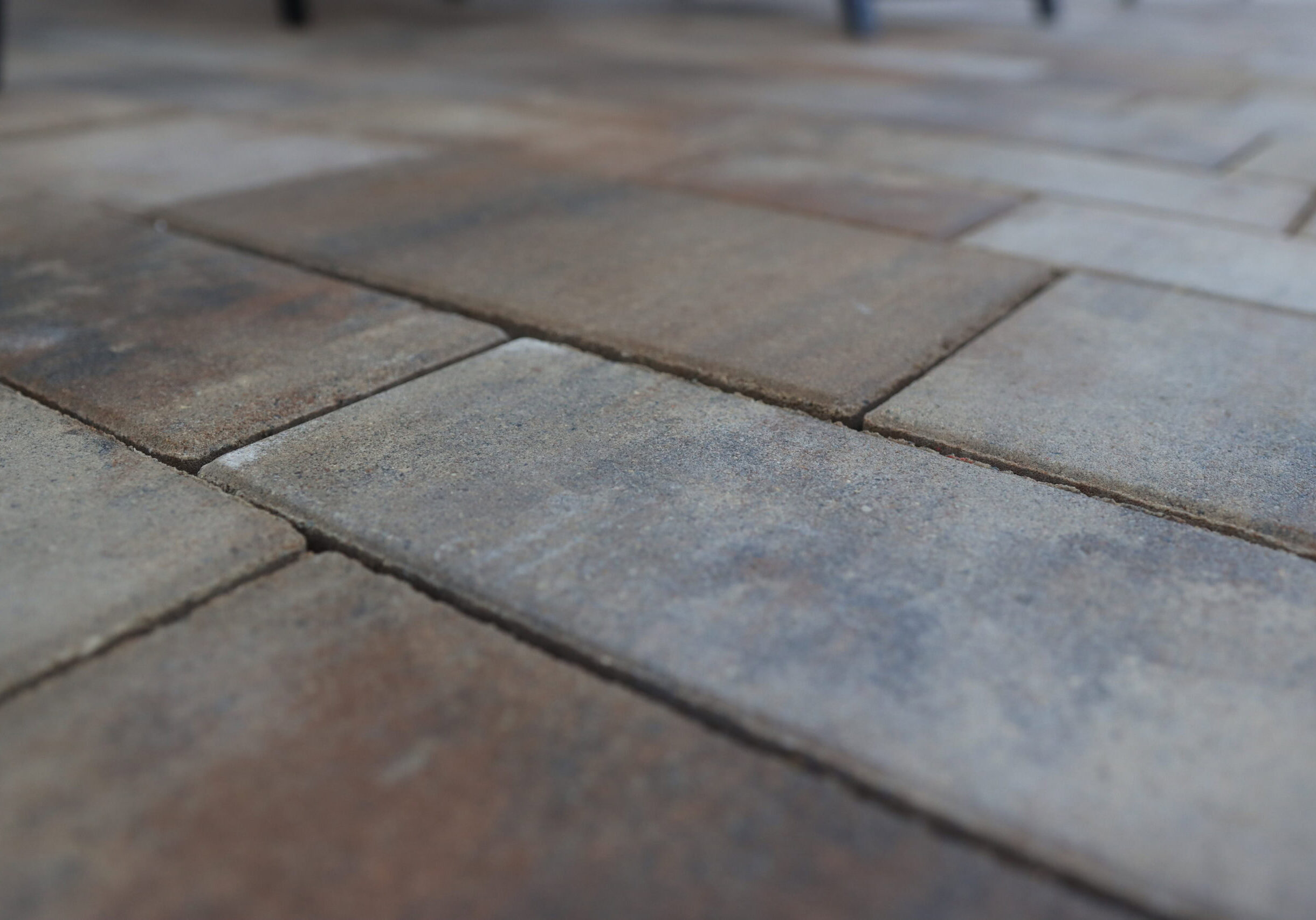 Closeup landscape photo of multiple light brown and gray concrete brick pavers.