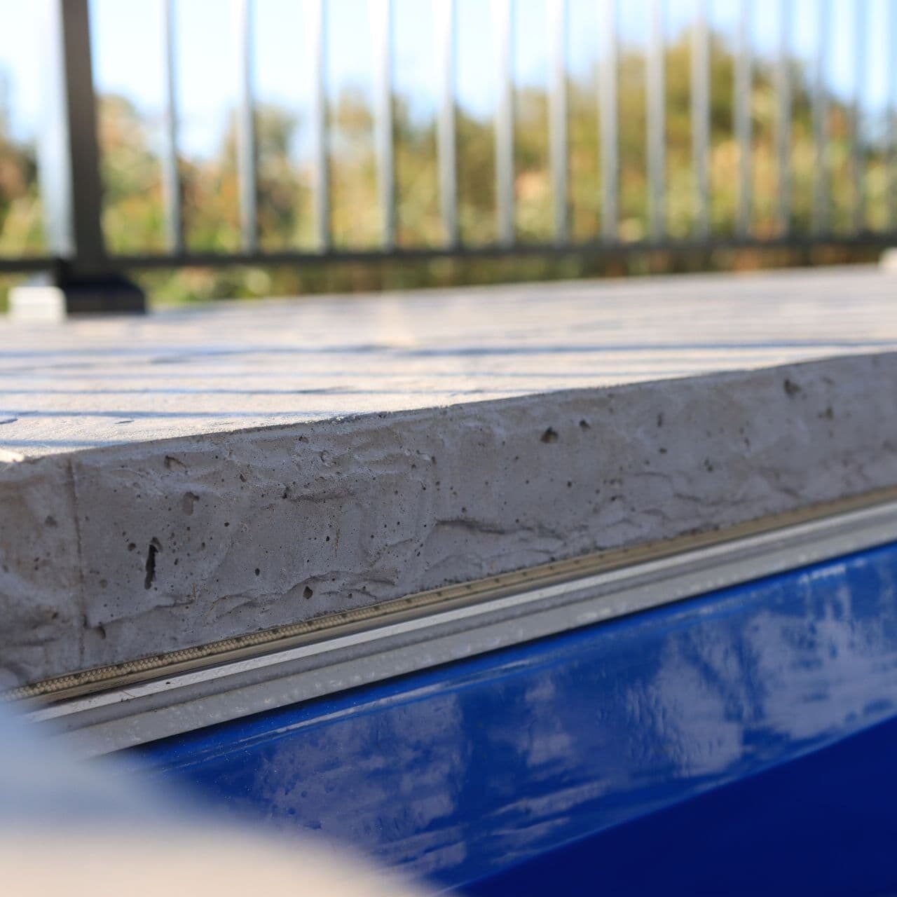 Closeup photo of textured concrete pool coping on the outside of an inground pool.