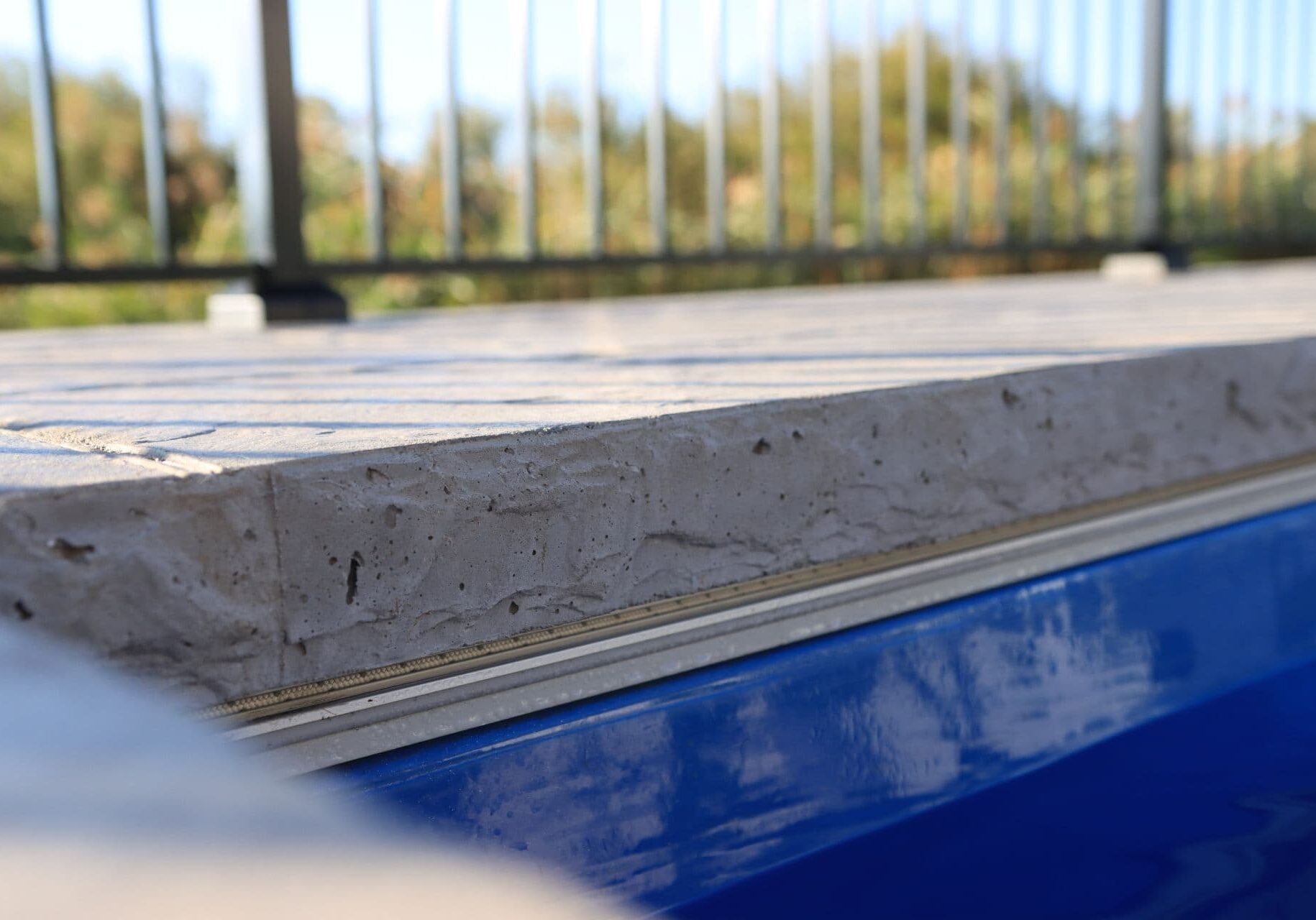 Closeup photo of textured concrete pool coping on the outside of an inground pool.