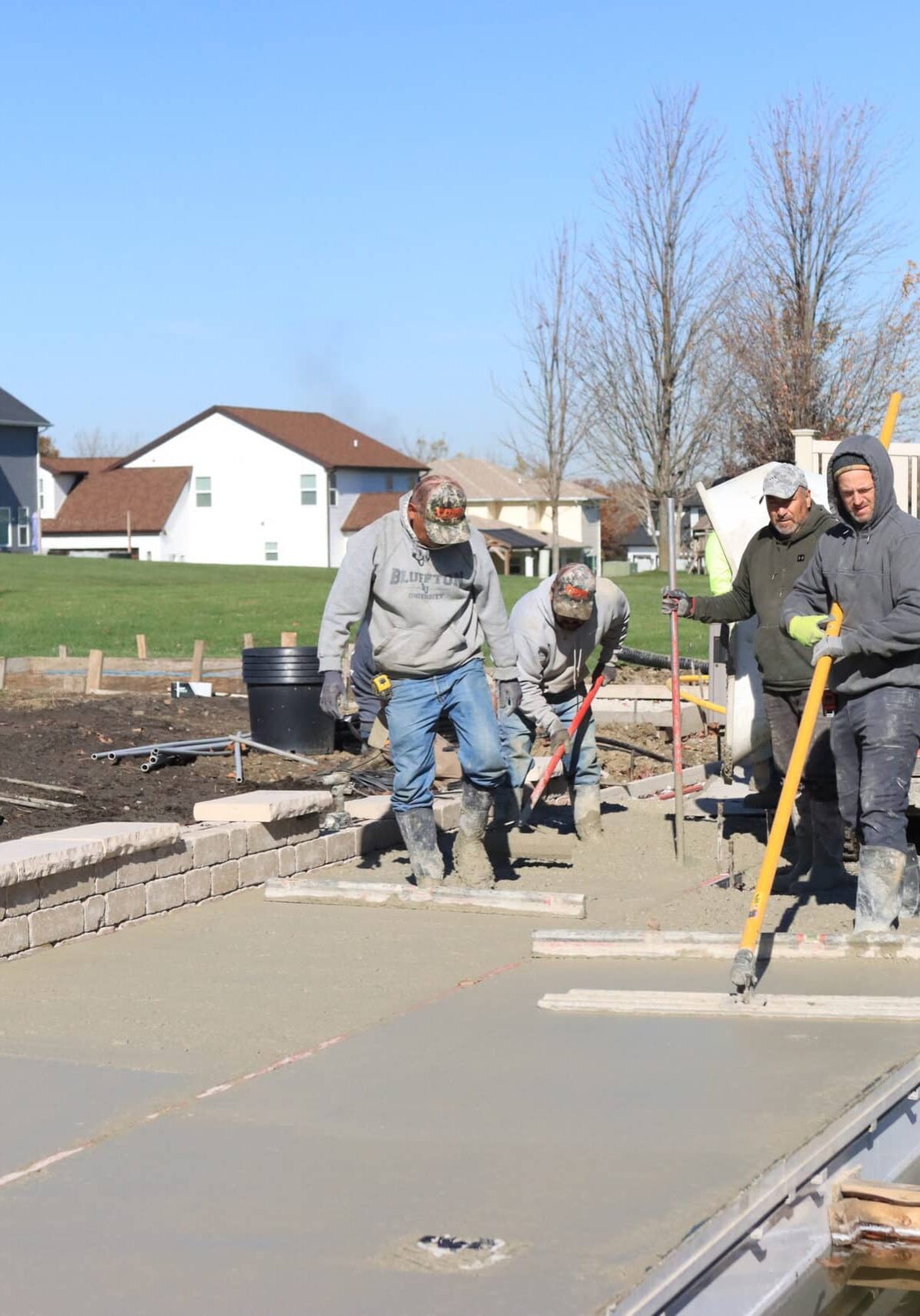 Workings flattening concrete around an inground pool.