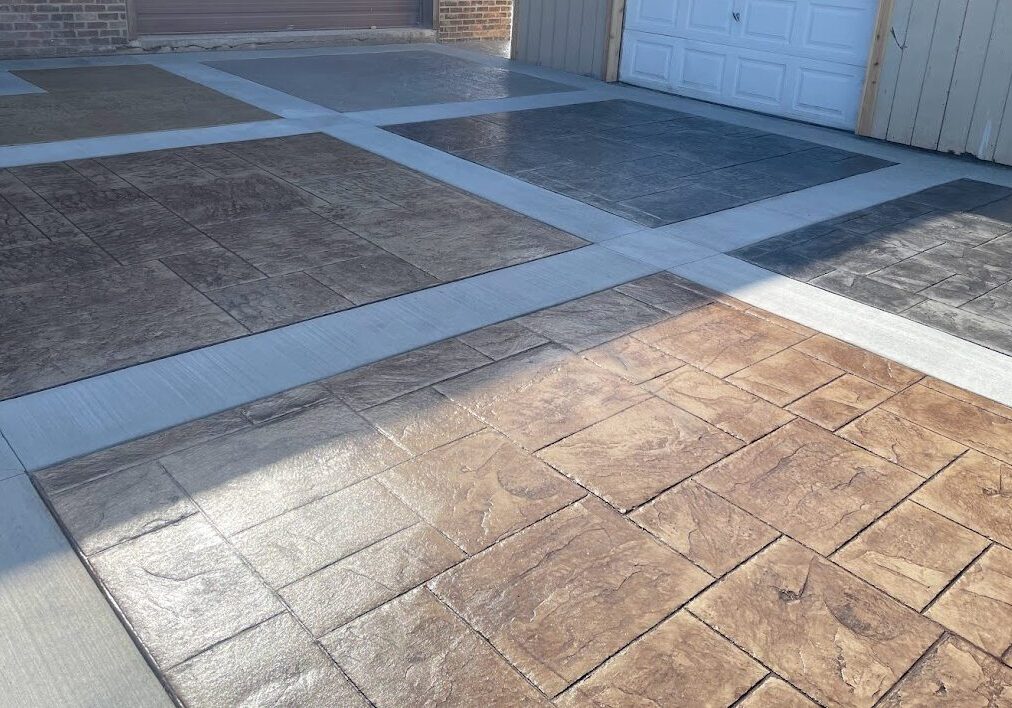 Photo of an area in front of a garage featuring six squares of different stamped designs and colors.