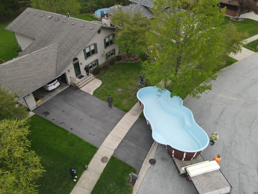 a pool being delivered through the front yard of a persons house in indiana