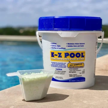 Square photo of a ten-pound bucket of E-Z POOL concentrated pool blend, alongside a scooper containing a light-green powder, both of which are sitting in front of an inground pool. Grass and the sky can be seen in the background behind the pool.