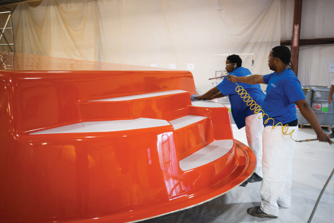 Two men building the outside of a fiberglass pool shell. 