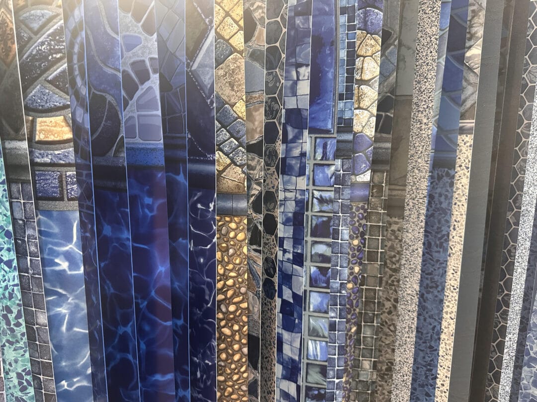 Photo of several different vinyl liner patterns draped next to one another.